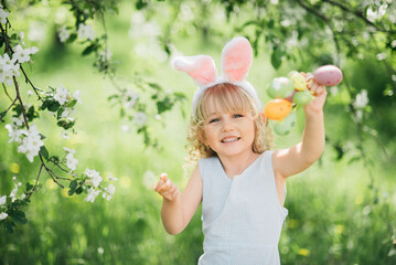Easter egg hunt. Girl child Wearing Bunny Ears Running To Pick Up Egg In Garden. Easter tradition....