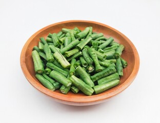 High angle view of long beans (Vigna Unguiculata ssp. Sesquipedalis) that have been cut into pieces in a wooden bowl on a white background.