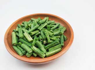 Long beans (Vigna Unguiculata ssp. Sesquipedalis) that have been cut into pieces in a wooden bowl on a white background. High angle view. 