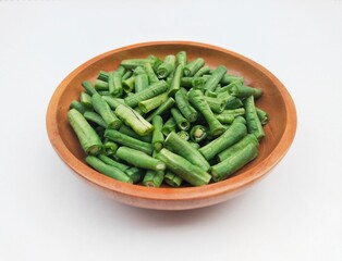 Long beans (Vigna Unguiculata ssp. Sesquipedalis) that have been cut into pieces in a wooden bowl on a white background. High angle view. 
