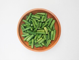 Long beans (Vigna Unguiculata ssp. Sesquipedalis) that have been cut into pieces in a wooden bowl on a white background. Top of view. 
