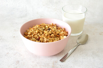 Granola in pink bowl with a glass of milk