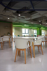 Restaurant with a lot of white chairs and tables. The chairs are mostly empty