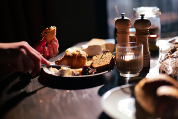Breakfast with dark rye bread, croissant, coffee and cheese in morning sunlight