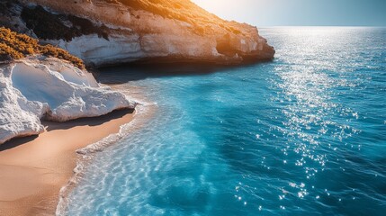 Beautiful beach with a rocky shoreline and a calm blue ocean. The sun is shining brightly, creating a warm and inviting atmosphere