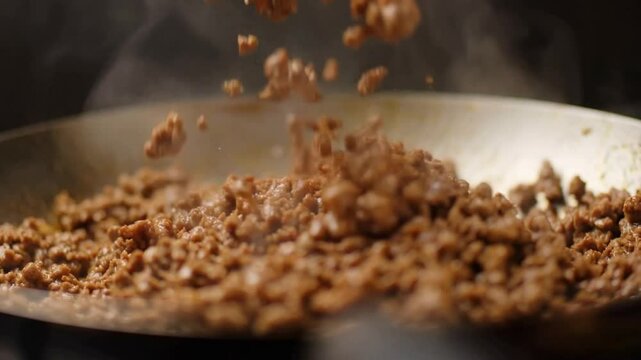 Juicy seasoned ground beef sizzling in a hot frying pan
