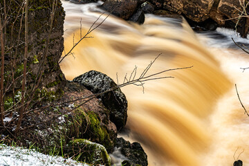 winter landscape with rapid river flow, blurred water surface, blurred movement, rapid stream of wild river