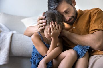 Close up of caring dad comforting his little daughter, coping with hard period of life, gently...
