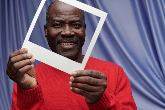 Smiling Man Framing Face with Photo Border in Hand