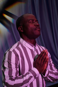 Man Standing with Praying Hands and Closed Eyes