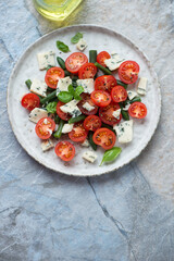 Cherry tomato, green beans and blue cheese salad, vertical shot on a blue and beige granite background with space, above view