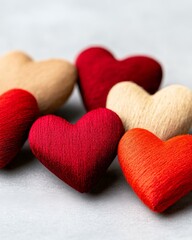 Obraz premium Collection of handcrafted fabric hearts in red beige and black arranged aesthetically on soft white surface symbolizing warmth love and emotional connections in lifestyle imagery