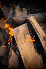 wood logs stacked burning with orange flames, soft focus close up, abstract backdrop