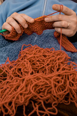 Red tangled thread with  defocused Womans  hands knitting with a crochet hook and soft focus close...