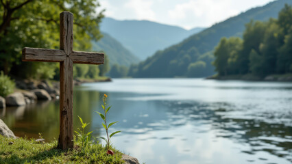 Cross standing near a river with a mountainous background.