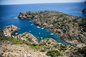 Aerial view of a rocky Mediterranean cove with boats anchored in turquoise waters