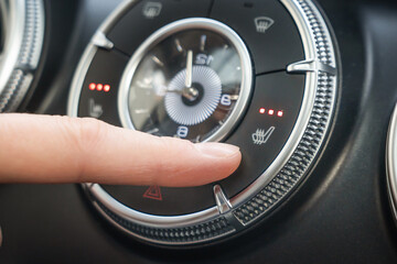 Turning on the three-level seat heating in the car, the finger presses the button. A closeup image featuring a finger skillfully adjusting the temperature controls on a modern cars sleek dashboard.