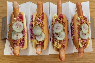 4 dänische hot dogs mit Zwiebeln, Gurken, Ketchup, Senf und Mayonnaise.