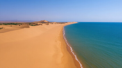Aerial view of golden sand dunes meeting tranquil blue ocean, showcasing beauty of nature contrasts. serene landscape invites exploration and adventure