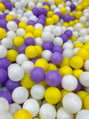 Lot of small ball on kids playground, purple, yellow and white. 