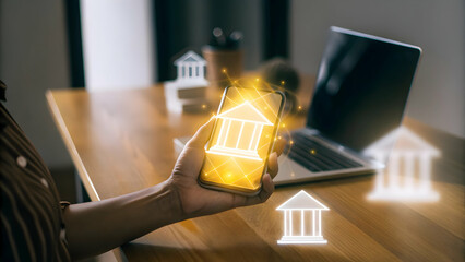 Experience the Future of Banking: Hand Holding a Mobile Phone with Holographic Banking App in a Home Office Setup - Highlighting Convenience and Security of Digital Banking