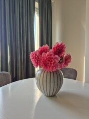 Vase with pink flower on a white table