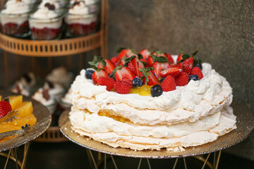 Pavlova meringue cake with fresh strawberries and blueberries. Light and airy dessert with whipped cream. Perfect sweet treat for special occasions. Gourmet fruit pastry on an elegant plate.