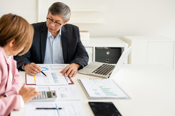 Fototapeta premium Business team two happy busy executives working together using calculator in office. Senior businessman manager showing presentation to mature investor, consulting client partner at work meeting..