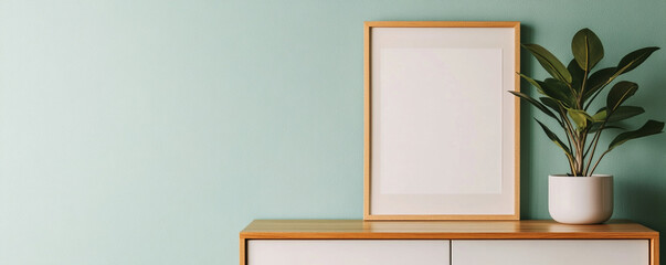 Minimalist decor with a frame and plant on a modern cabinet.