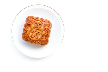 Overhead view of a mooncake on a white plate with gold rim. Bright lighting shows intricate details and the '雙' (shuāng) character, meaning PAIR
