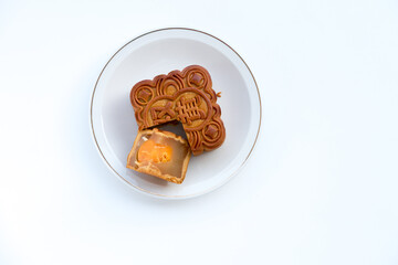 Mooncake with cut slice revealing filling and egg yolk. Overhead shot on a white plate. Bright lighting shows intricate details, the '雙' (shuāng) mean PAIR