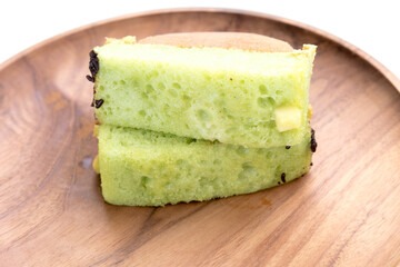 Pukis slices on a wooden plate. Soft, light green cake with a honeycomb texture.