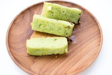 Pukis slices on a wooden plate. Soft, light green cake with a honeycomb texture.