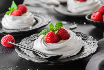 pavlova meringue dessert with raspberries and cream on a black background