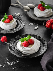 pavlova meringue dessert with raspberries and cream on a black background
