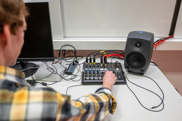 Sound engineer working on audio mixing console with cables connected