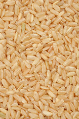 A close-up, overhead shot of a pile of brown rice grains showcases their natural texture and earthy color, emphasizing their wholesomeness and dietary value