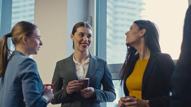 Group of professional women chatting in an office until one turns to a man, sparking envy or judgment from another. Concept of workplace dynamics, subtle competition, and social tension