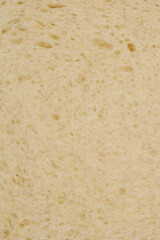 A close-up shot of a slice of white bread reveals its porous texture and light color, highlighting its soft and airy nature