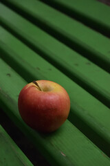 Single Red Apple on a Vibrant Green Bench in a Minimalist Composition