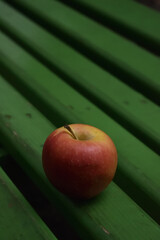 Single Red Apple on a Vibrant Green Bench in a Minimalist Composition