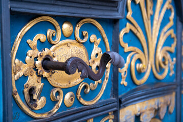 A beautifully decorated metal door handle against the background of a blue door.