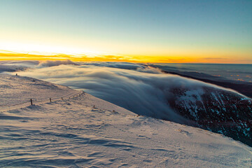 Zachód słońca w polskich górach Karkonosze na Śnieżka, po zmierzchu ponad chmurami.