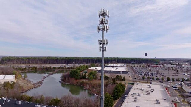 Aerial video from a drone zooming in and rising up of a cellular communications tower and antenna in a major shopping area.