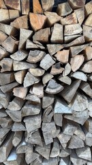 Stack of Natural Firewood Logs Arranged in Rustic Outdoor Setting. Neatly stacked firewood pieces showcasing textures of natural wood grains, ideal for rustic or seasonal themes.