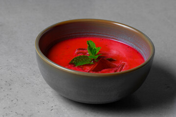 Cold beetroot soup with mint in a bowl on a gray background