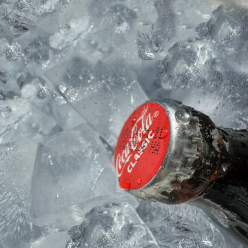 Coca Cola classic bottle close up with red cap with ice on the background