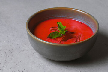 Cold beetroot soup with mint in a bowl on a gray background