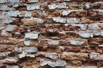 Close-up of an old, weathered brick wall with rough, textured surfaces and eroded mortar. A rustic, aged background perfect for vintage, architectural, and grunge-style designs.
