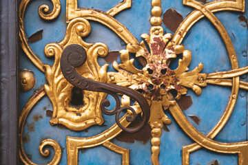 A beautifully decorated metal door handle against the background of a blue door.
